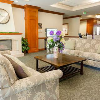 A cozy lobby area with sofas, a wooden table, and floral decor.