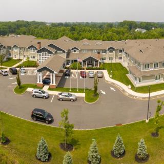 Aerial view of a residential complex with a parking lot and landscaped surroundings.