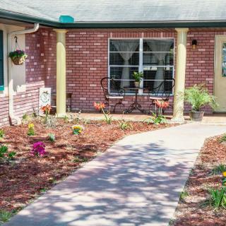 A welcoming brick house with a landscaped garden and a paved pathway leading to the porch.