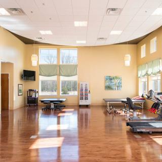 A spacious exercise and rehabilitation room with fitness equipment and therapy tables.