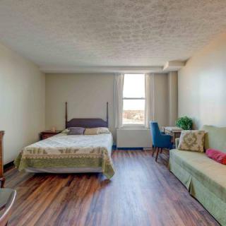 A cozy studio apartment with a bed, sofa, and a small table by the window.