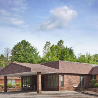 A single-story brick building surrounded by greenery under a blue sky with clouds.