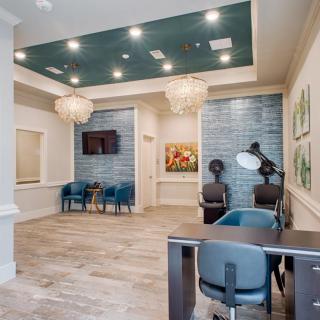 A modern waiting room with comfortable seating, decorative chandeliers, and artwork adorning the walls.