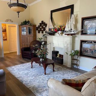 A cozy living room with nautical-themed decor, featuring a large mirror above the fireplace and plush seating around a coffee table.
