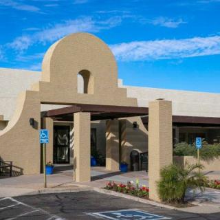 The entrance to a building featuring desert-style architecture with a parking lot and handicap spaces.