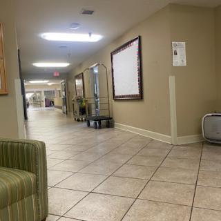 A spacious and well-lit hallway featuring tiled flooring and a seating area.