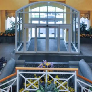 A spacious indoor entrance with glass doors and decorative plants.