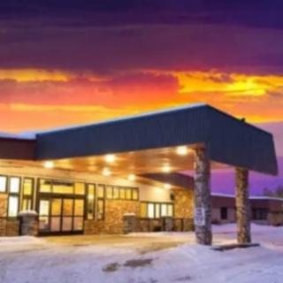 A building entrance illuminated at sunset with snow-covered ground.