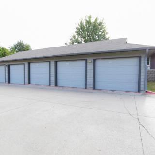 Row of garages with blue doors and a concrete driveway.