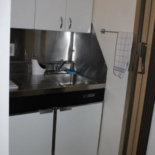 A compact kitchen area with a sink, cabinets, and metal backsplash.