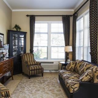 A cozy living room featuring patterned furniture and large windows.