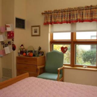 A cozy bedroom interior with a chair by the window and a dresser.
