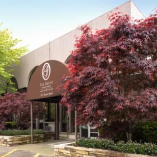 A building entrance with an awning and landscaped trees.