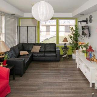 A cozy living room with modern decor featuring a black sofa, vibrant green walls, and wooden flooring.