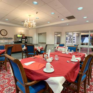 A neatly arranged dining room with red tablecloths, set for a meal.