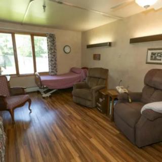A cozy nursing home room with a bed, recliner, and large window.