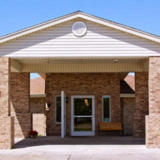 A brick building entrance with a covered entryway and a bench.