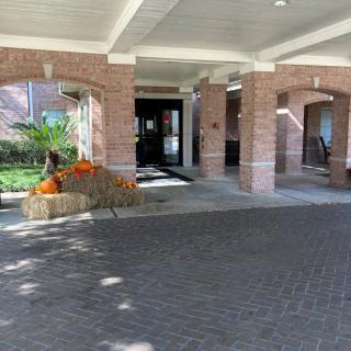 The entrance to a building features pumpkins and hay bales as seasonal decorations under a covered walkway.