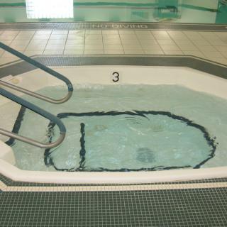 An indoor hot tub with bubbling water and tiled surroundings.