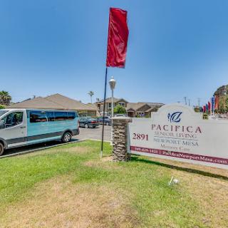 Entrance to Pacifica facilities with a van parked nearby and a flag waving in the breeze.
