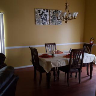 A cozy dining room with a table set for four, featuring warm yellow walls and elegant lighting.