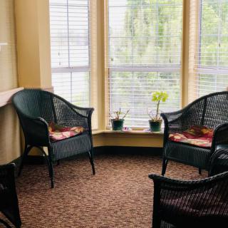 A cozy seating area with wicker chairs and natural light from large windows.