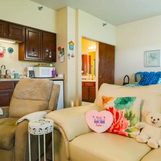 A cozy living room with a couch, colorful cushions, and an adjoining kitchen area.