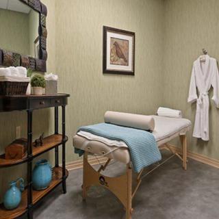 A serene massage room equipped with a treatment table and a robe, designed for relaxation.