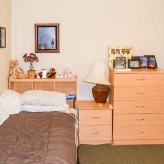 A cozy bedroom with a single bed, a dresser, and decorative items.