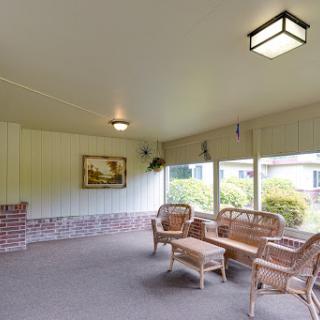 A cozy indoor porch featuring wicker furniture and large windows, perfect for relaxation.