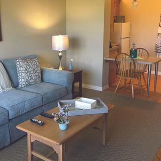 A cozy living room with a blue sofa, coffee table, and adjacent dining area leading to a kitchen.