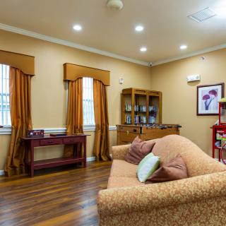 A cozy living room with warm tones, featuring a couch, wooden floors, and elegant decor.