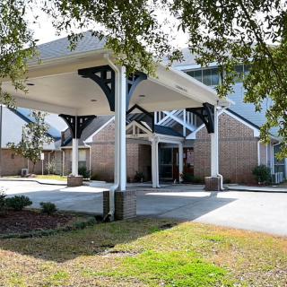 An entrance with a canopy structure leading to a building, surrounded by trees.