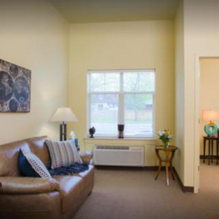 A cozy living room with a leather couch, lamps, and decorative elements.