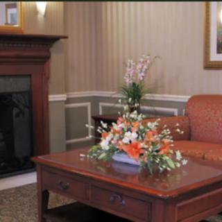 A cozy living room with a fireplace, a sofa, and a coffee table adorned with a floral arrangement.