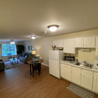 A cozy apartment with an open floor plan, featuring a small kitchen and a living area.