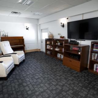 A cozy living room with a piano, bookshelves, and comfortable seating.