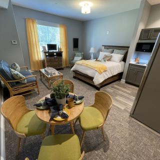 A cozy studio apartment featuring a bed, a seating area, and a dining table.
