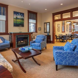 A cozy living room featuring blue armchairs, a fireplace, and elegant decor.