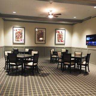 A neatly arranged room with tables and chairs, featuring framed artwork on the walls and a checkered carpet.