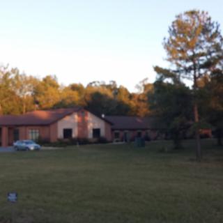 A suburban house surrounded by trees and a large lawn at sunset.