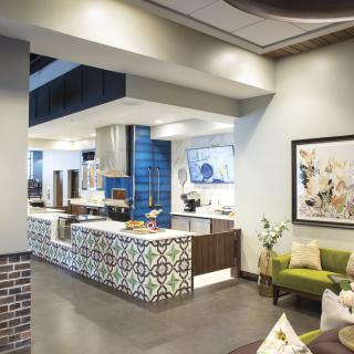 A modern cafe interior featuring decorative tiled counters, comfortable seating, and contemporary artwork.