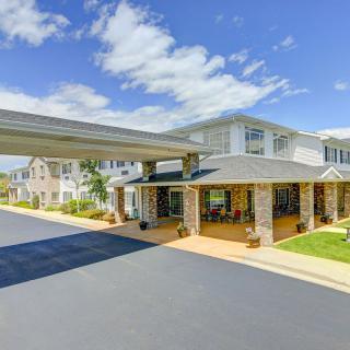 A sunny day view of a residential building entrance with a covered driveway.