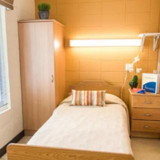 A cozy and minimalist bedroom with a single bed, wardrobe, and warm lighting.