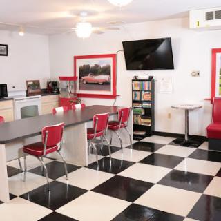 A vibrant retro-style kitchen with red accents and black-and-white checkered flooring.