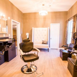 A well-lit beauty salon interior featuring chairs and mirrors.