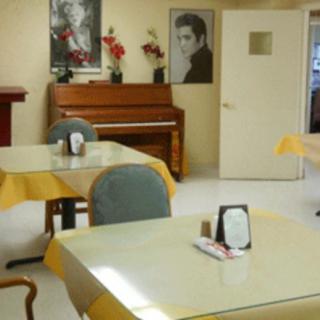 A cozy dining room featuring tables and chairs, with a piano and framed posters on the wall.