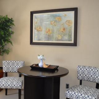 A cozy waiting area featuring stylish chairs, a circular table, and framed artwork.