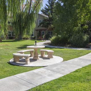 A serene park area with stone tables and benches surrounded by lush greenery.