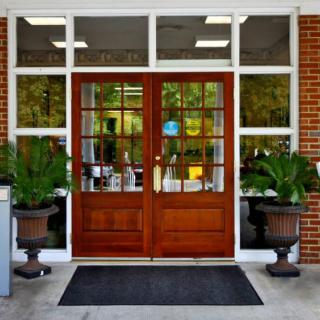 A symmetrical entrance with large wooden doors and glass windows, flanked by potted plants.